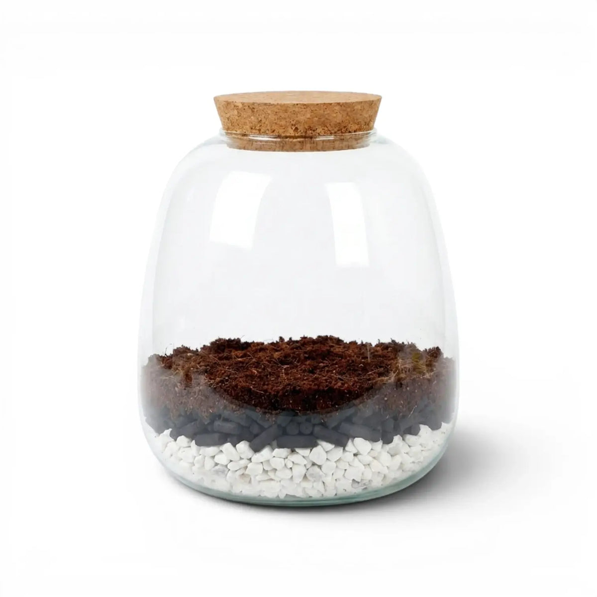Glass jar with a cork lid containing soil, activated carbon pellets and small gravel stones on a white background