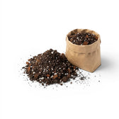 Brown paper bag filled with aroid potting mix next to a pile of aroid potting mix on a white background